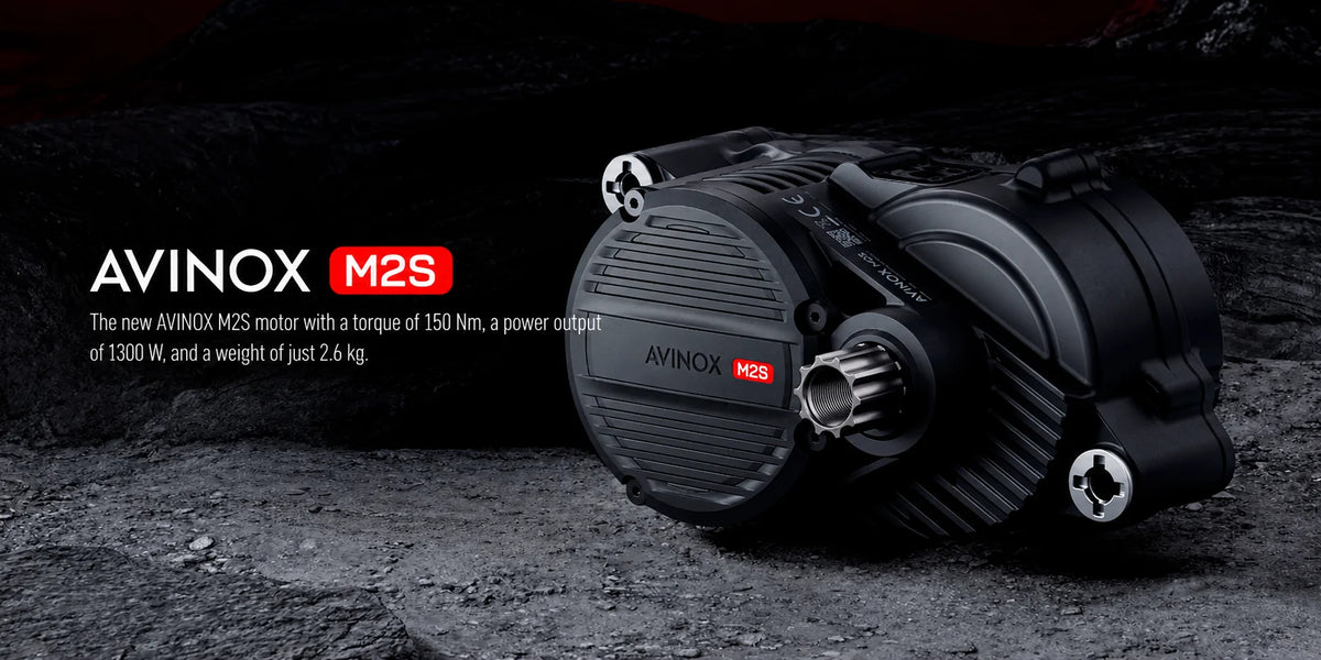 A black cylindrical electric motor labeled 'AVINOX M2S' with a small red AVINOX logo, shown on a dark rocky surface with promotional text on the left.